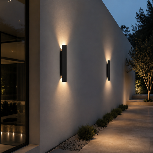 Appliques murales design alignées le long d'un mur de terrasse au crépuscule, éclairant une allée bordée de galets