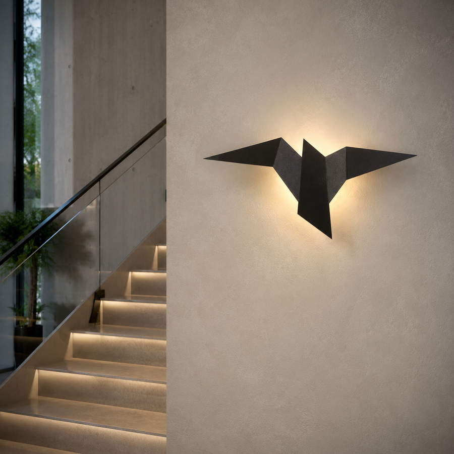 Applique murale originale origami oiseau noire installée dans une cage d'escalier, projetant une lumière chaude sur un mur clair